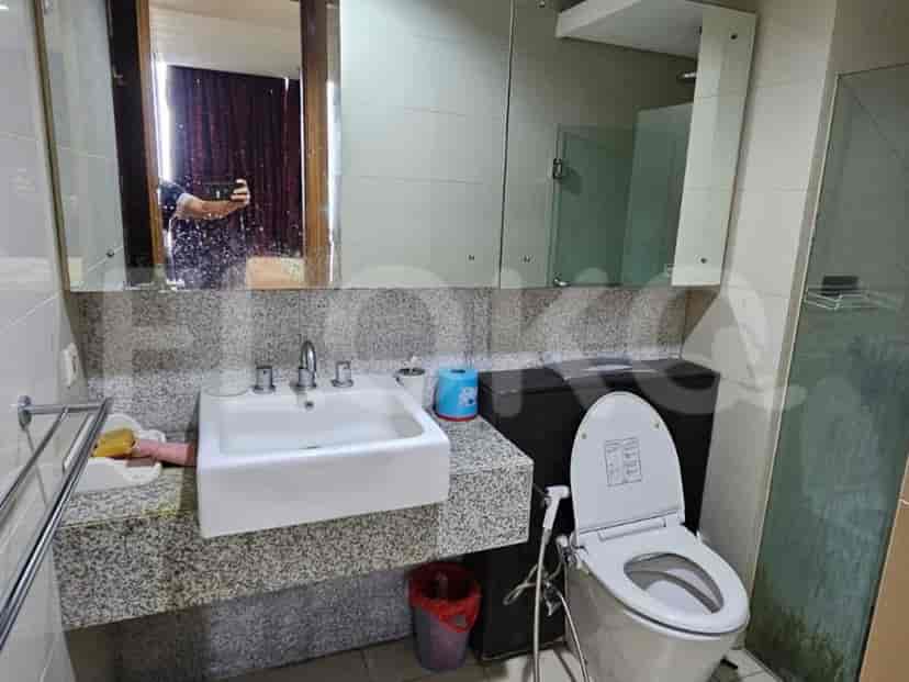 A bathroom with a white sink on a granite countertop, toilet, and a glass shower enclosure.