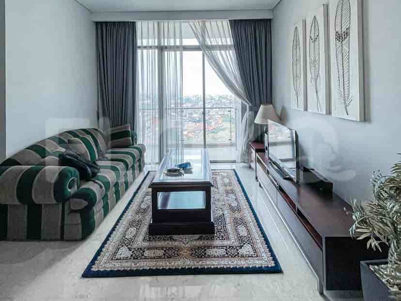 A living room with a striped sofa, coffee table, rug, and a TV.