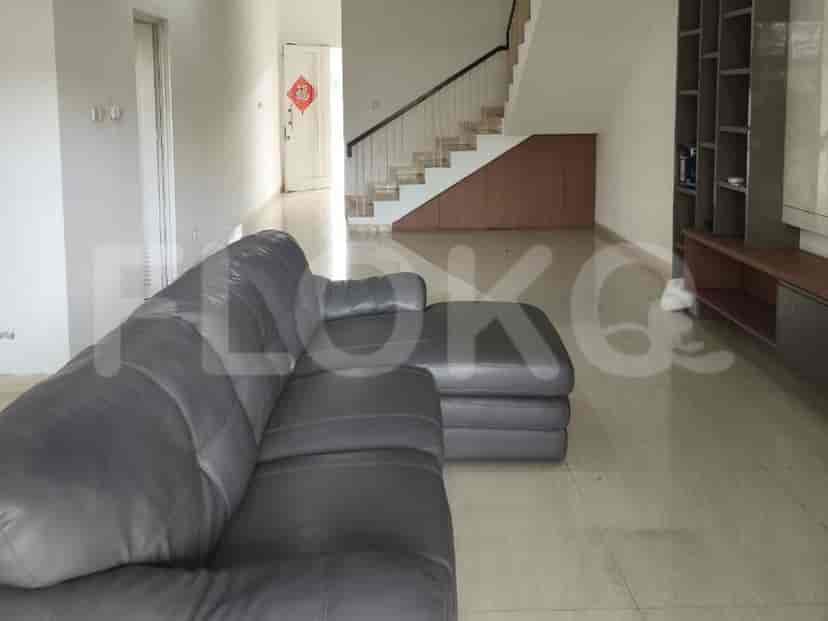 A spacious living room with a large grey sectional sofa, a staircase, and a bookshelf.