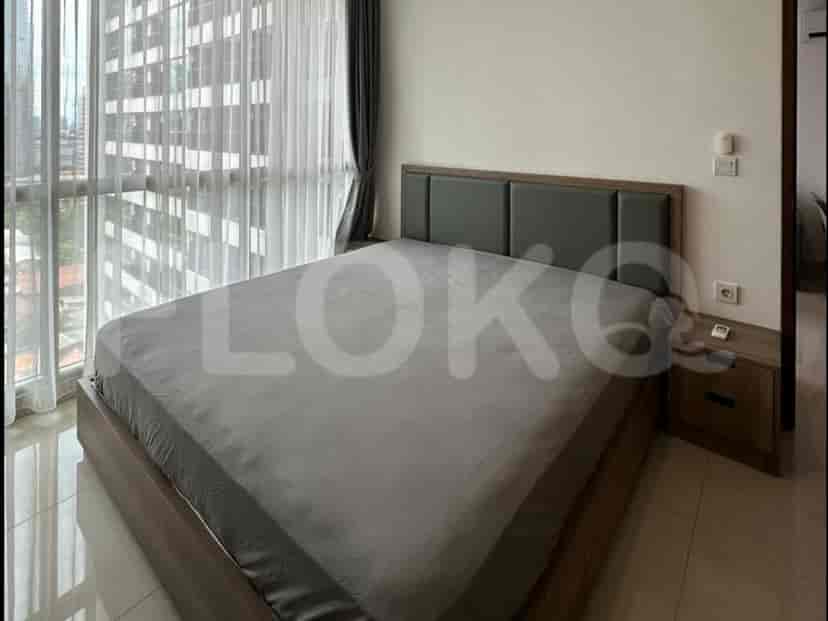 A bedroom with a large bed, nightstand, and a window with city views.