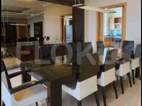 A formal dining room with a large rectangular table and chairs, adjacent to a kitchen area.