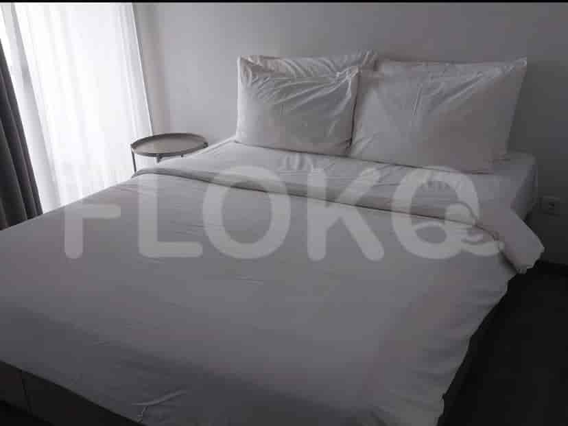 A bedroom featuring a queen-size bed with white linens and pillows, next to a bedside table.