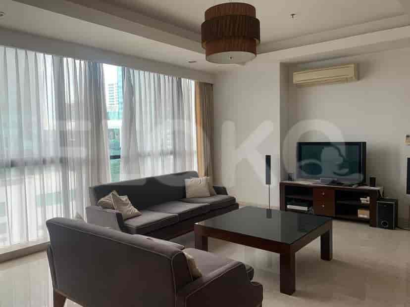 A modern living room with grey sofas, a large coffee table, and floor-to-ceiling windows.