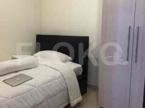 A minimalist bedroom with a single bed, a wardrobe, and a laptop on the bed.