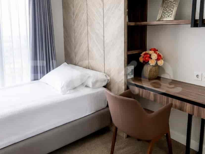 A minimalist bedroom with a single bed, a wooden desk with a chair, and built-in shelving.
