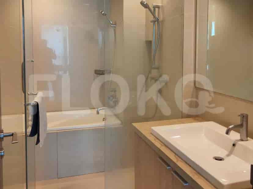 Kamar mandi modern dengan bak mandi, pancuran, dan meja rias dengan wastafel.