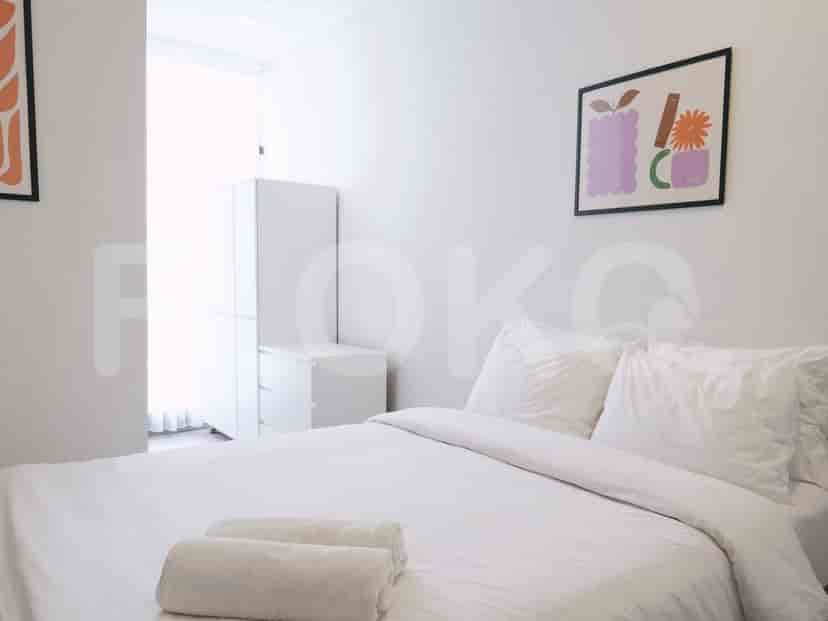 A bedroom with a white bed, white rolled towels, and minimalist artwork on the wall.