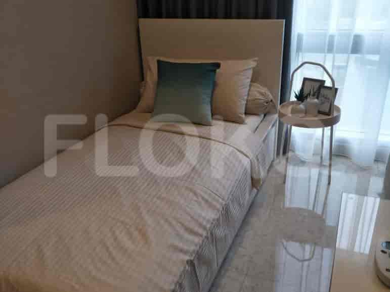A bedroom with a single bed, a bedside table, and a round side table.