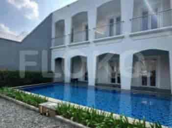 A swimming pool adjacent to a white building, with an outdoor area.