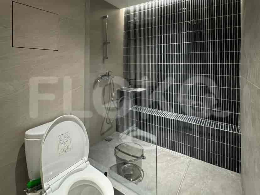Kamar mandi dengan pancuran, toilet, dan partisi kaca.