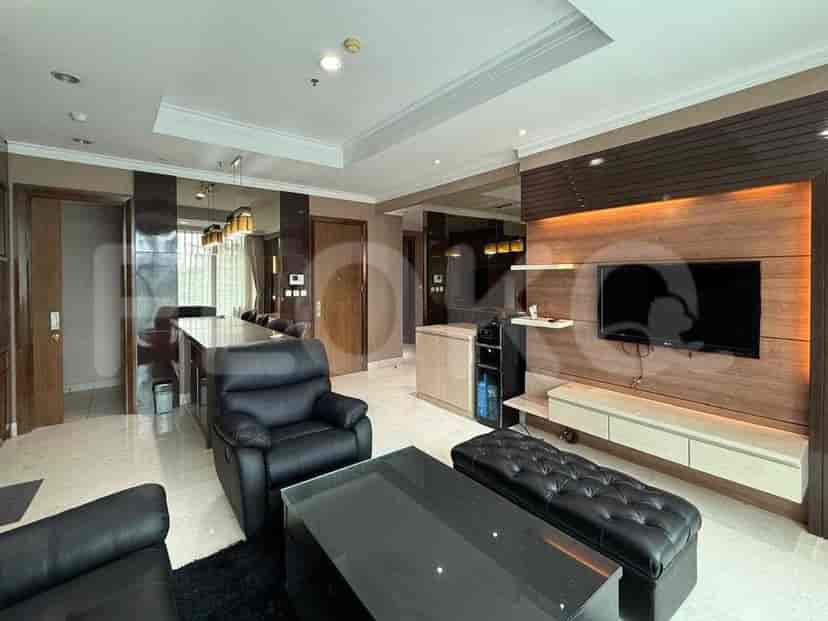 A modern living room with black leather sofas, a glass coffee table, a dining area with pendant lights, and a wooden accent wall with a TV.