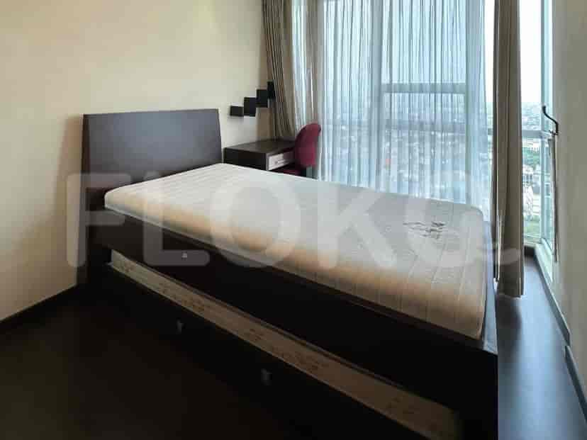 A bedroom with a single bed, a small desk, and a large window.