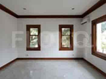 A spacious bedroom with two windows, wood-framed windows, and a neutral color scheme.