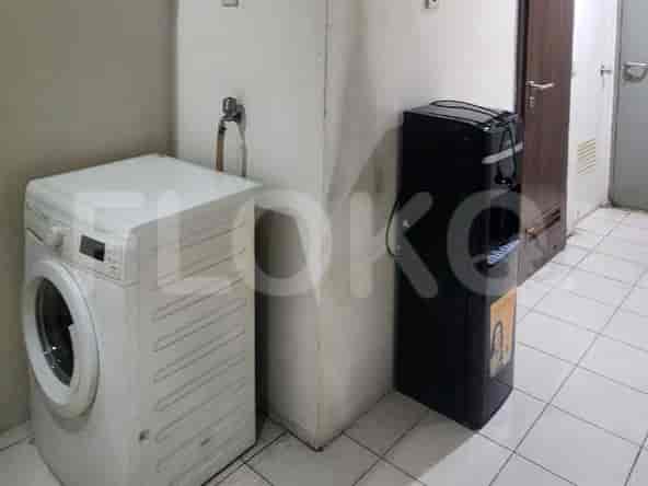 Laundry area with a washing machine, water dispenser, and tiled flooring.