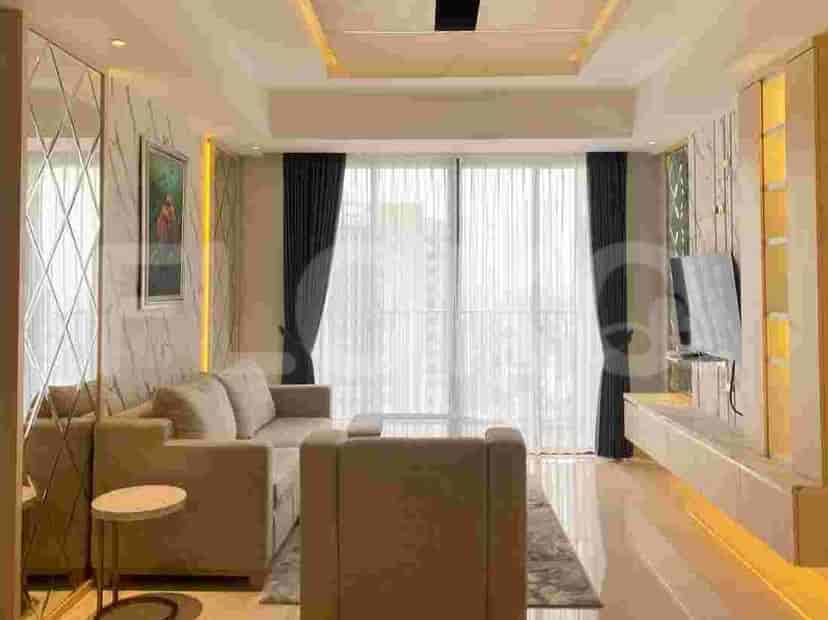 A modern living room with a large sofa, TV, and floor-to-ceiling windows.