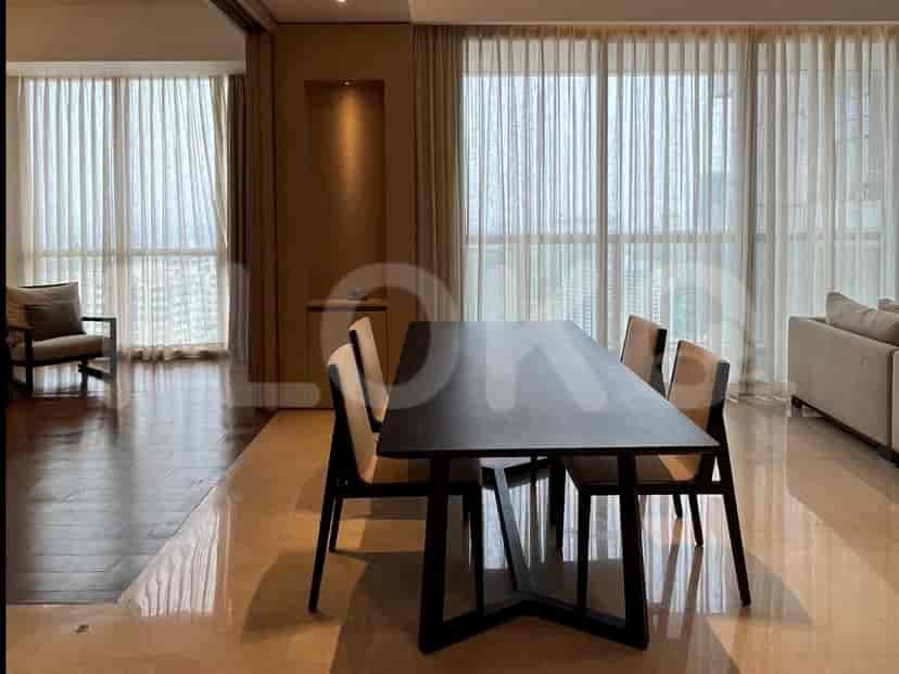 A dining area with a rectangular table and chairs, adjacent to a living area with sheer curtains.