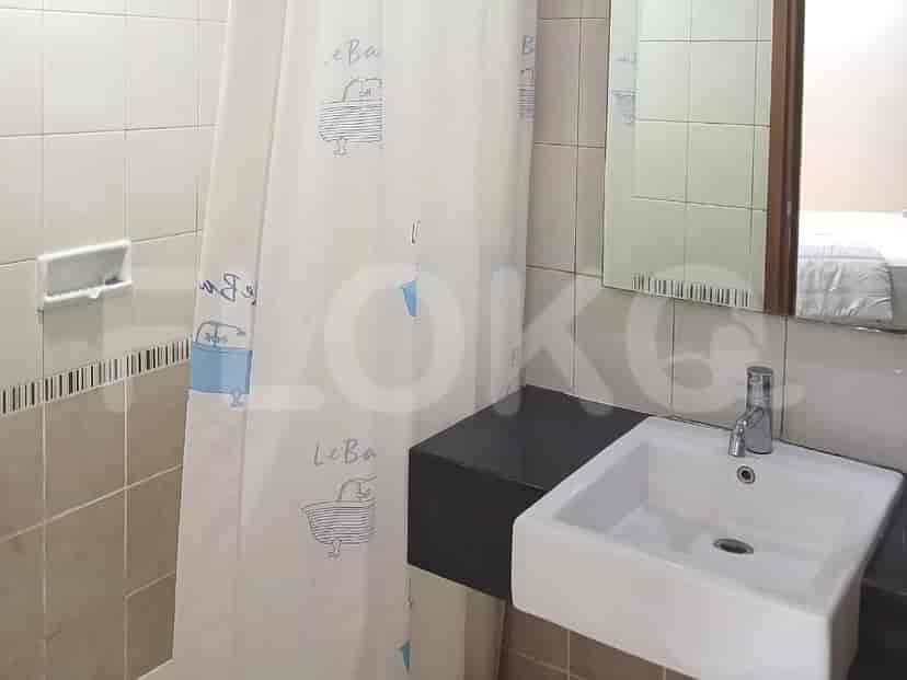 A bathroom with a sink, shower curtain, and a mounted soap dispenser.