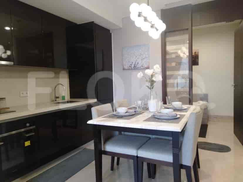 An open-plan kitchen and dining area with a marble dining table and sleek kitchen cabinets.