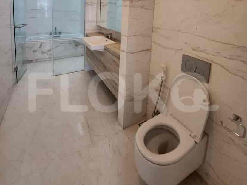 Kamar mandi modern dengan lantai marmer, toilet putih, dan wastafel.