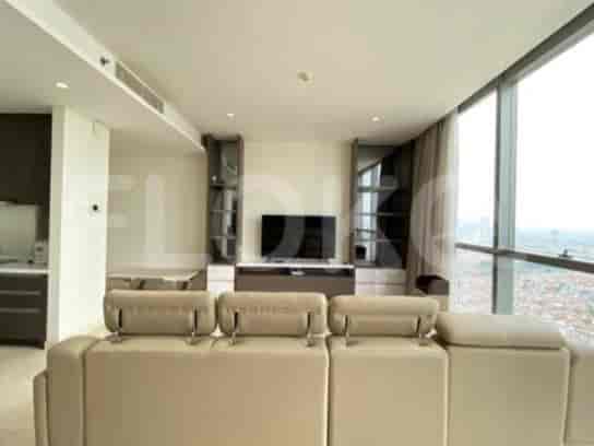 A contemporary living room with a large sectional sofa, entertainment unit with a TV, and floor-to-ceiling windows offering a city view.