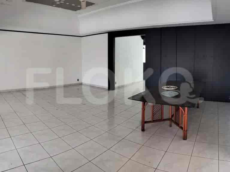 A large, open-plan living area with tiled floors, white walls, and a dark accent wall with a built-in counter.