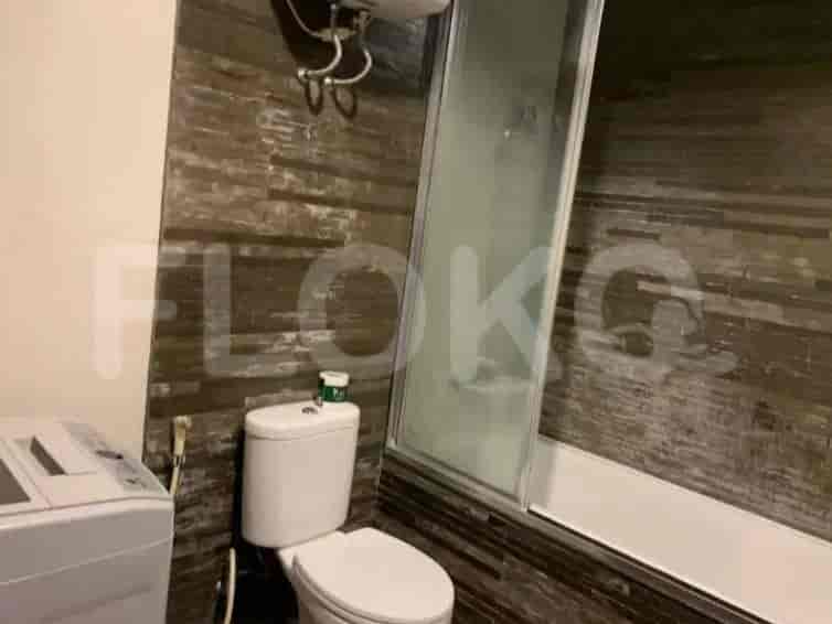 Kamar mandi dengan toilet, mesin cuci, dan bak mandi dengan pancuran.