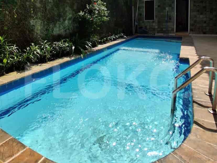 A rectangular swimming pool with blue tiles and a stone-tiled surround, featuring metal railings.