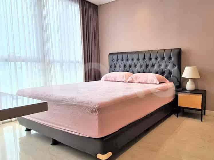 A bedroom featuring a king-size bed with a tufted headboard, pink bedding, and a bedside table with a lamp.