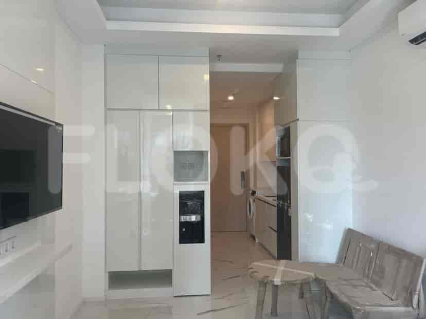 A compact living area with a kitchenette, integrated cabinets, a water dispenser, and a sofa.