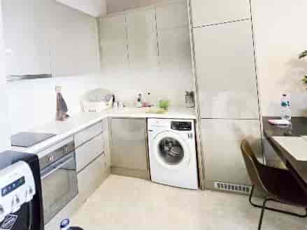A modern kitchen with white cabinetry, a washing machine, and a built-in oven.