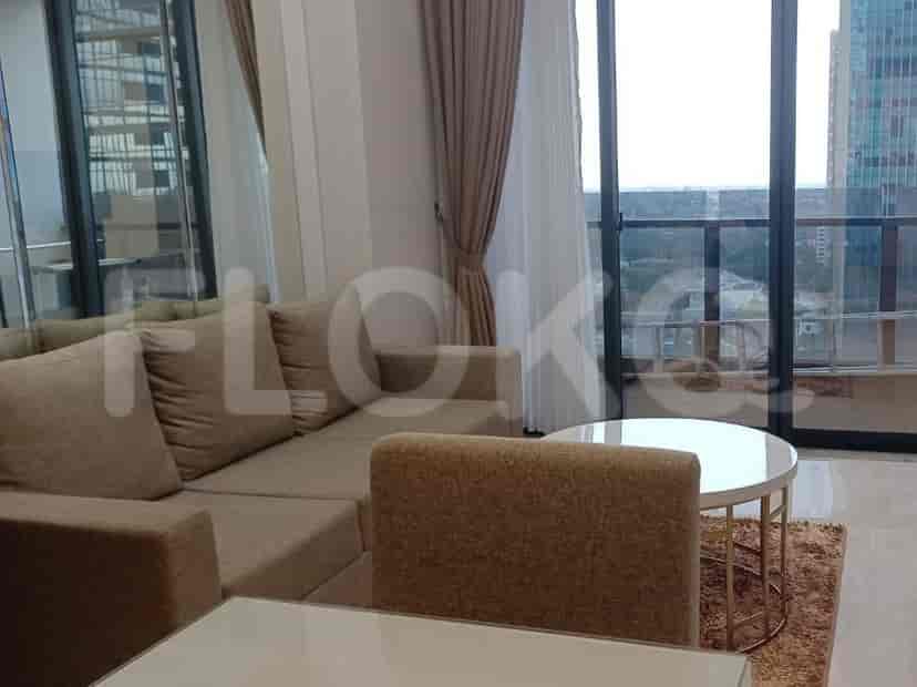 A modern living room with a beige sofa, a round coffee table, and large windows with curtains, showing a city view.