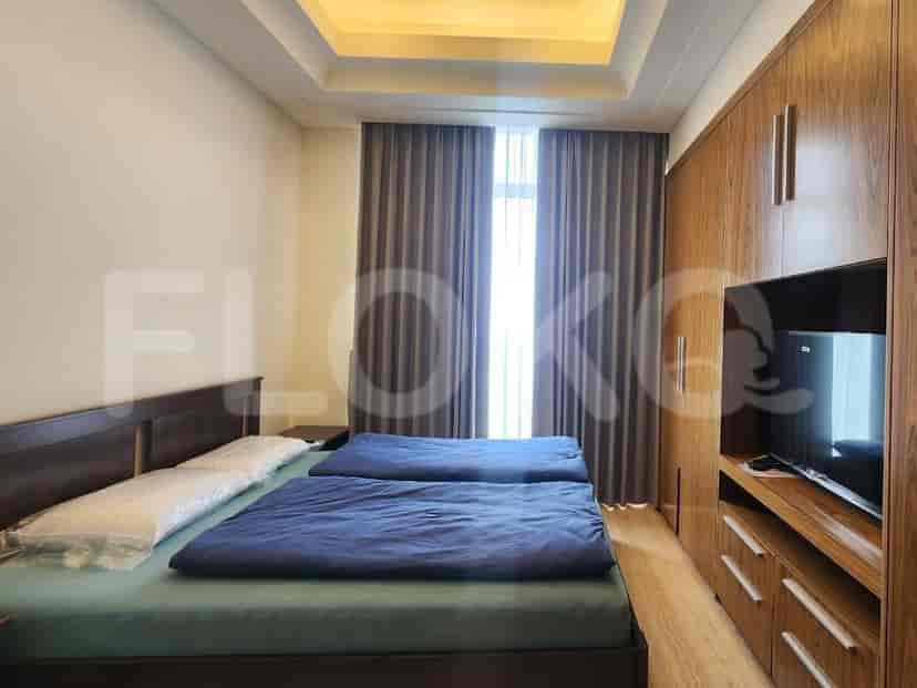 A bedroom with two single beds, a large wooden wardrobe, and a TV.