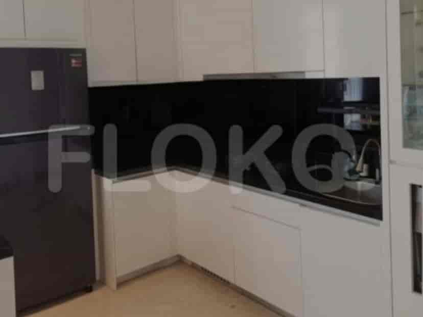 A modern kitchen with white cabinets, black backsplash, and a refrigerator.