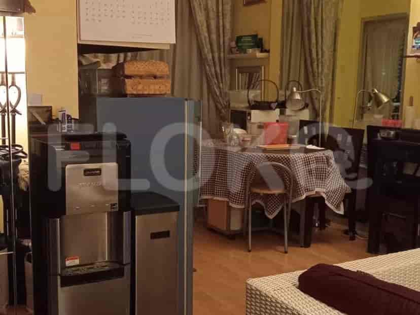 Area with a dining table, chairs, a water dispenser, and a refrigerator.