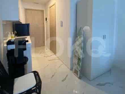 A hallway with a small kitchen counter, a TV, a chair, a large cabinet, and an ironing board.