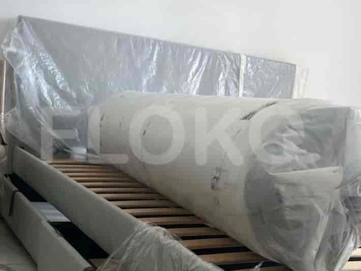 A bedroom with a bed frame and mattress covered in protective plastic.
