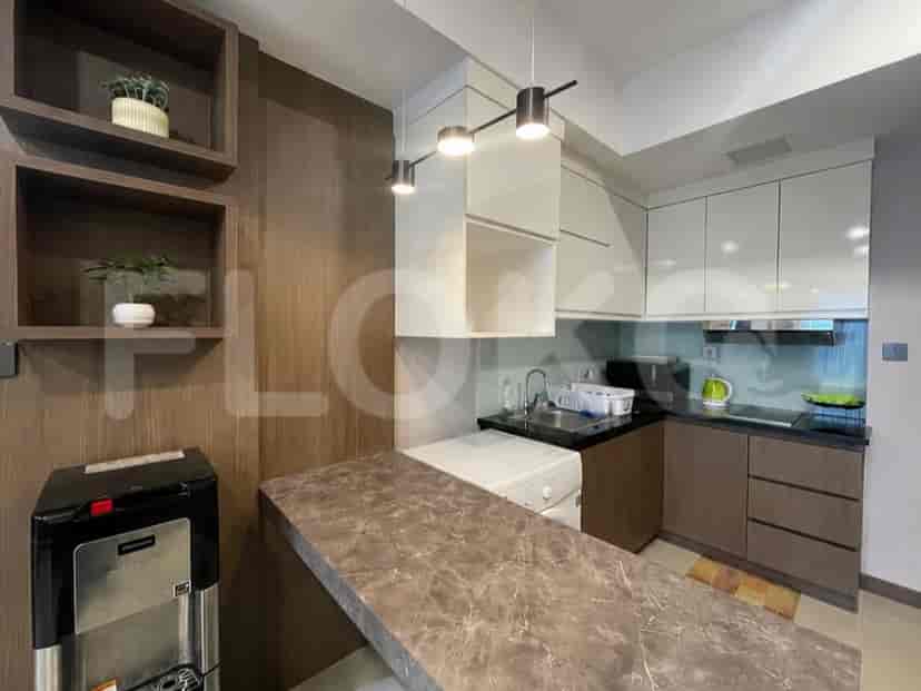 A compact kitchen with white and brown cabinets, a countertop, and a water dispenser.