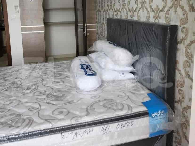 A bedroom with a large bed covered in plastic, a headboard, and pillows.