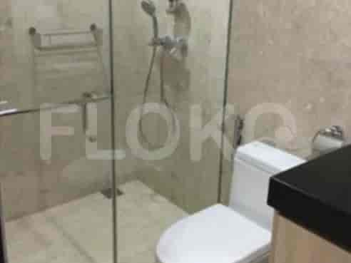 Kamar mandi modern dengan shower tertutup kaca, toilet putih, dan ubin bermotif marmer.