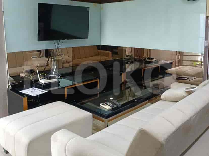 A modern living room featuring a large sectional sofa, a glass-top coffee table, and a wall-mounted TV.