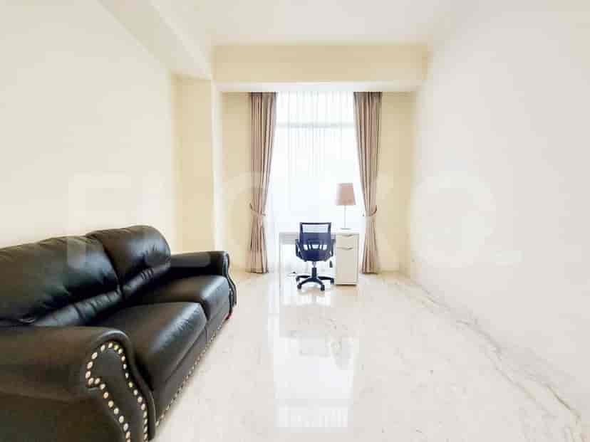 A home office setup with a leather sofa, desk, and a window offering natural light.
