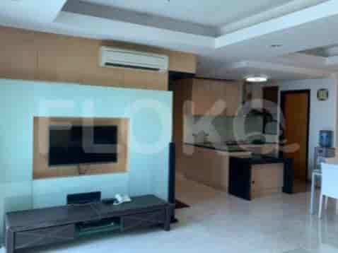 A bright living room with a television console, an air conditioning unit, and an open view of the kitchen.
