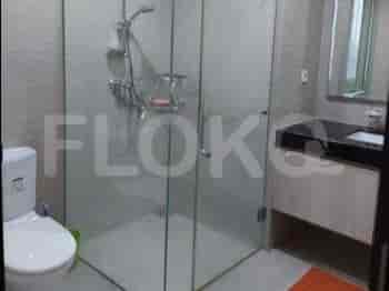 Kamar mandi modern dengan penutup pancuran kaca dan wastafel.