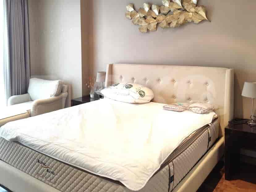 A king-sized bed with a tufted headboard, dressed in white linens, with bedside tables and lamps.