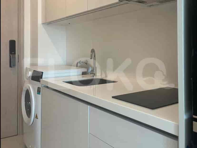 A close-up of a modern kitchenette counter with a sink, faucet, electric stove, and washing machine.