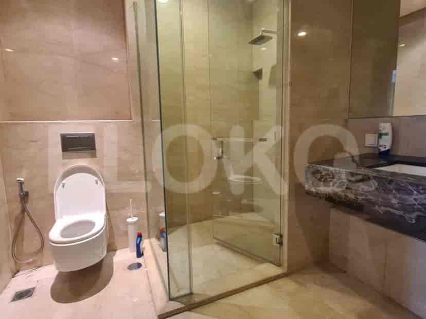 Kamar mandi modern dengan pancuran berkaca, toilet, dan wastafel.