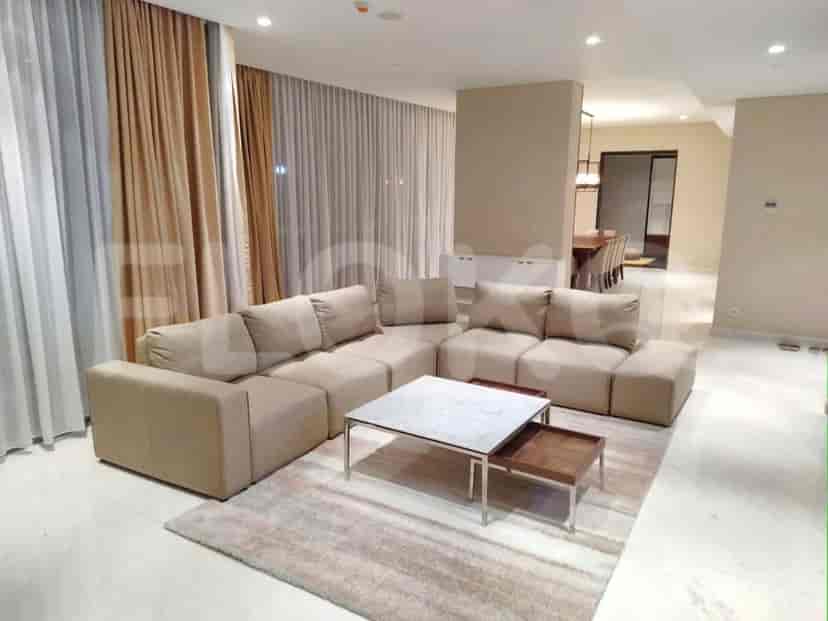 A spacious living room featuring a large sectional sofa, a marble-top coffee table, and sheer curtains.