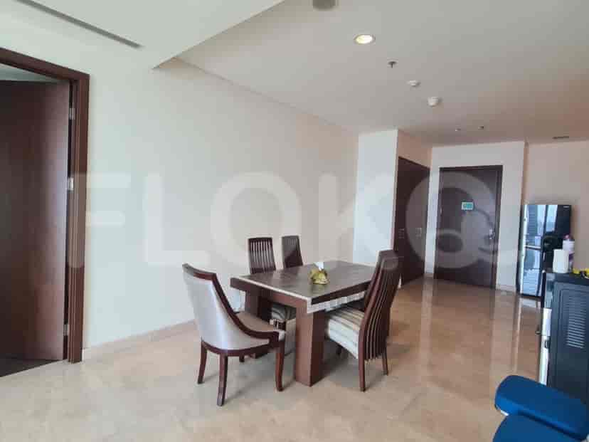 Area makan dengan meja kayu persegi panjang dan kursi, menciptakan ruang yang nyaman untuk makan.