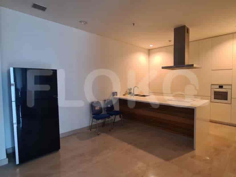 Dapur modern dengan lemari es, meja, dan lemari, menawarkan ruang memasak yang fungsional.
