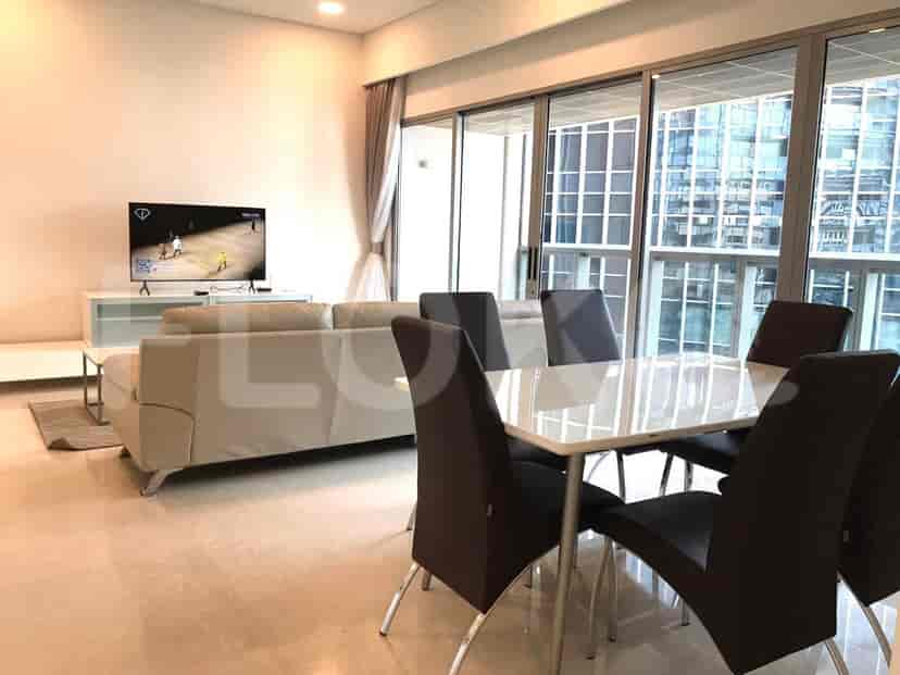 A living and dining area with a sofa, dining table, chairs, and a large window overlooking a city view.
